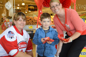 Michael Kilday receiving a red donut from Coles team member Ann Marie Stott-Lucas and Ashlee Marmont.