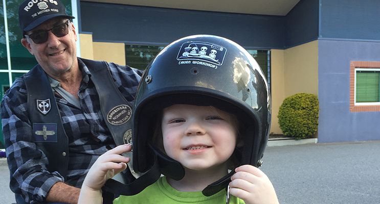 Three year old Xavier trying on a helmet for size with his new friend, Longrider member, Wheels.
