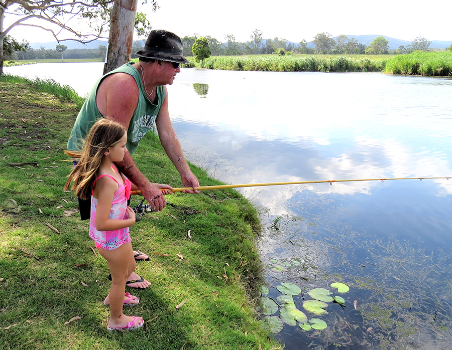 FAMILY FISHING: Brett Shultz helps Grace McRae cast a line along the banks of the Myall River