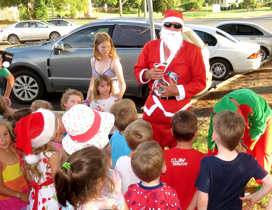 COMMUNITY SPIRIT: SANTA distributes Christmas treats to the children.  