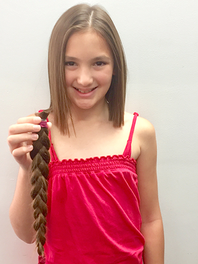 Anjah Jedniuk holding her selfless donation - 36cm of hair for children with cancer.