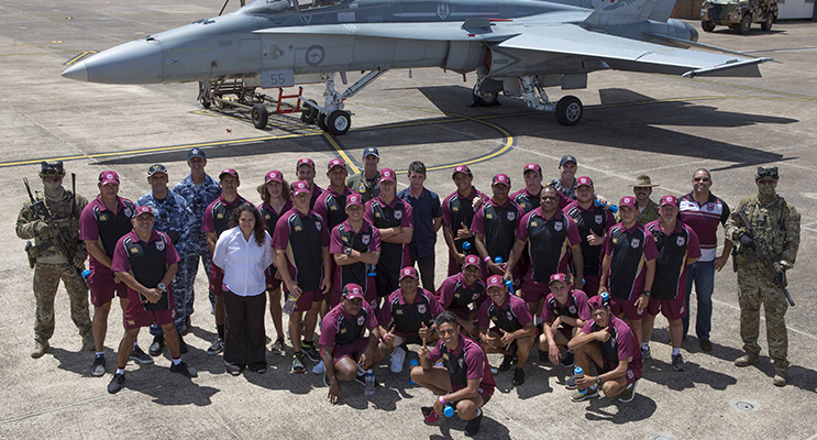 NRL Indigenous U16 team viewing Air Force assets at RAAF Base Williamtown including an F/A-18 Hornet aircraft with a Panther Fire Truck and Bushmaster vehicle.