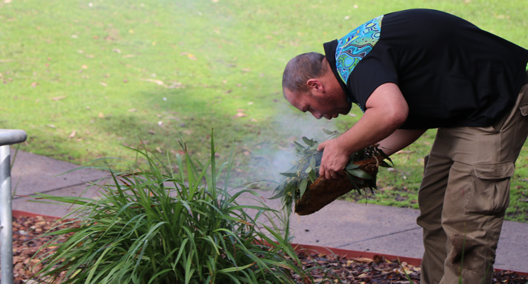 Brett Chambers, from the Worimi Green team, performing a smoking ceremony at the official opening. 