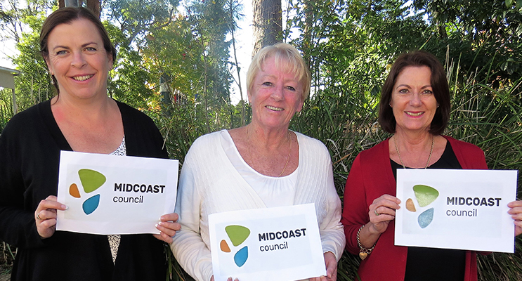 Local residents Linda Drenkhahn, Jennifer Hughes and Julie Worth examine the new MidCoast logo. 