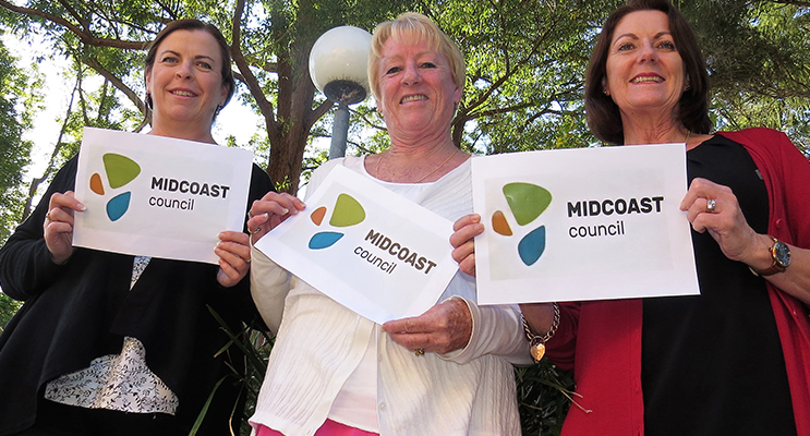 Local residents Linda Drenkhahn, Jennifer Hughes and Julie Worth examine the new MidCoast logo. 