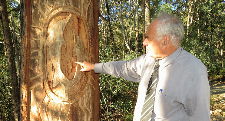 Land Council CEO Len Roberts examines the dolphin tree carving.    