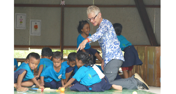 Adrienne Ingram hands out educational toys to pre-school children in Cambodia.
