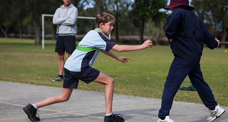 Physical Education: BCS Year 8 student Dane Pope joins in a game of grenade with Year 6 students at Tea Gardens. Photo: BCS