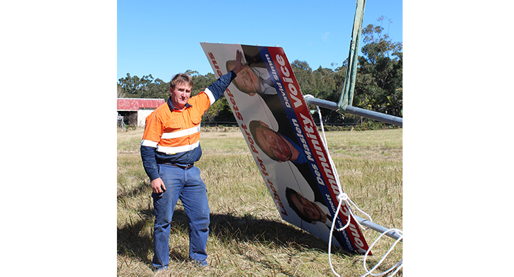 Des Maslen works to repair the sign on Nelson Bay Road.