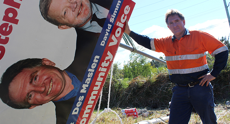 Des Maslen works to repair the sign on Nelson Bay Road.