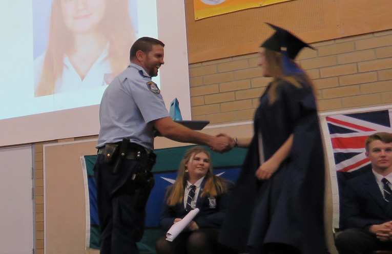 Senior Constable Ash Ray presents Kaitlyn Smart with her academic portfolio.