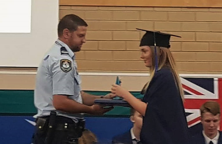 Senior Constable Ash Ray present Emma Miller with her academic portfolio.