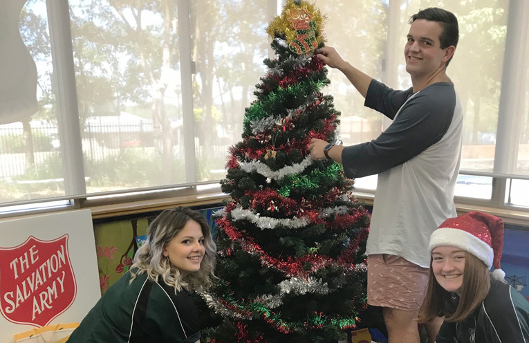 Rachael Teale, Connor Hall and Georgia Sulis placing items around the tree.