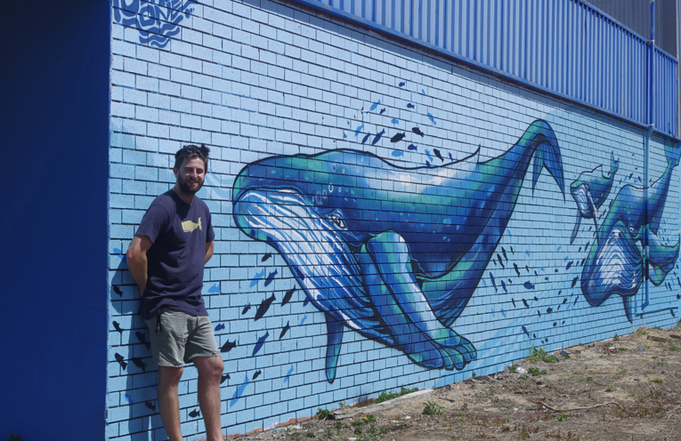 Nick Stuart with his whale migration mural at Anna Bay. Photo by Marian Sampson.