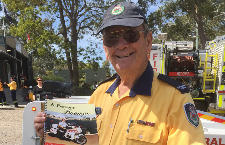 Bill Taylor with his book in front of the mini fire engine he created. 