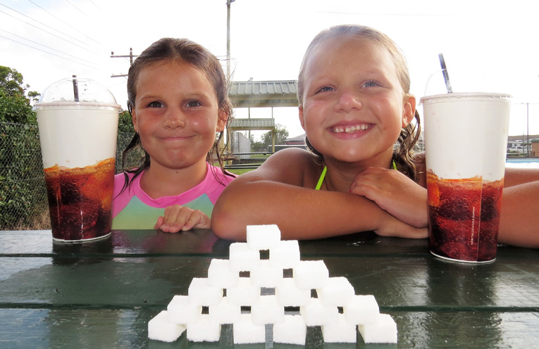 Lucy Collison and Bella Watling show the amount of sugar contained in a large frozen drink. 