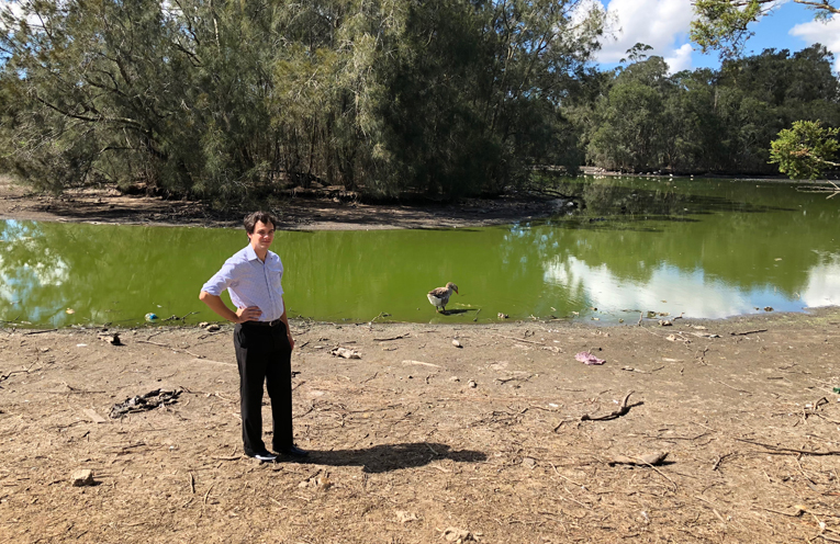 Councillor Arnott standing on the dry bed of the duck pond, which is usually filled with water past this point.