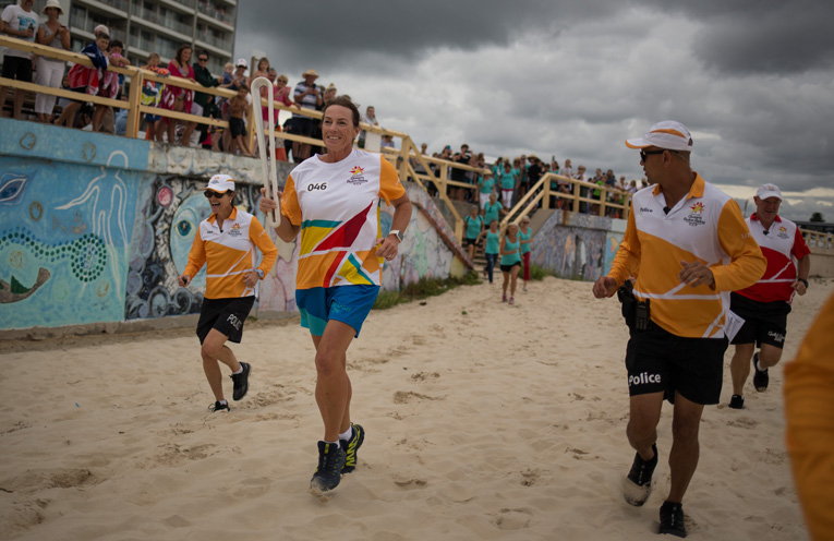 Batonbearer Laura Thurtell carries the Queen’s Baton onto Forster Beach. 