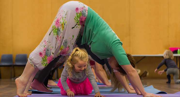 Cora crawls underneath yoga instructor, Aimee Angelique, in a downward facing dog tunnel routine.
