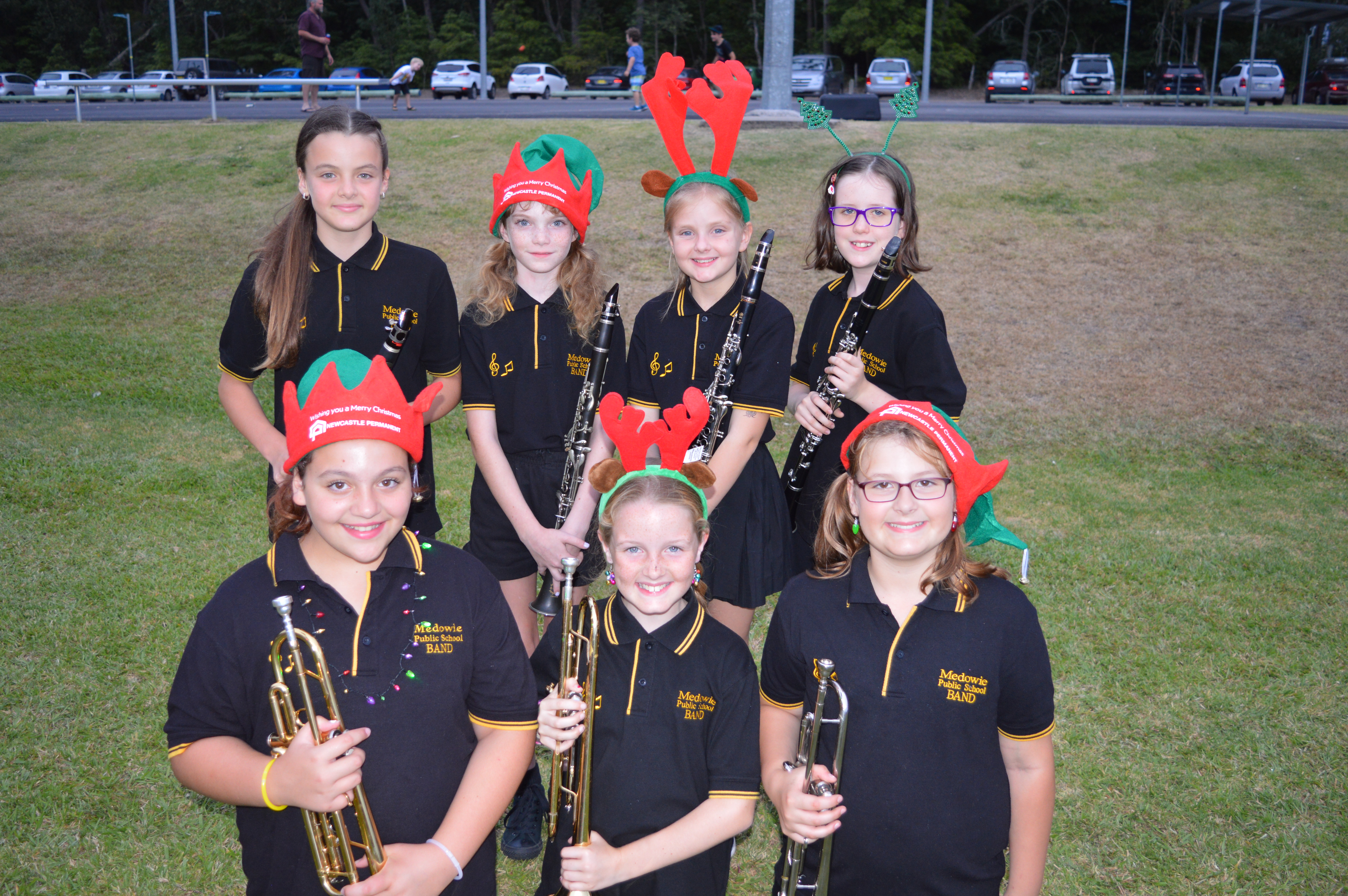 : [same as photo 3 but on a different angle]: Medowie Public School band members getting ready to play Jingle Bells and Santa Rocks. Front row: Kiah Skaines, Keira Thoburn, Abby Keeley. Back row: Lily Thurlow, Emersyn Towers, Yasmin McGarry, Charlotte Merriman.