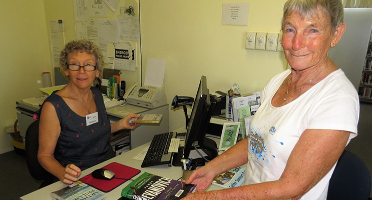 Volunteer librarian Beatrice Weeks assists Carol Tattersall at Bulahdelah Library. 