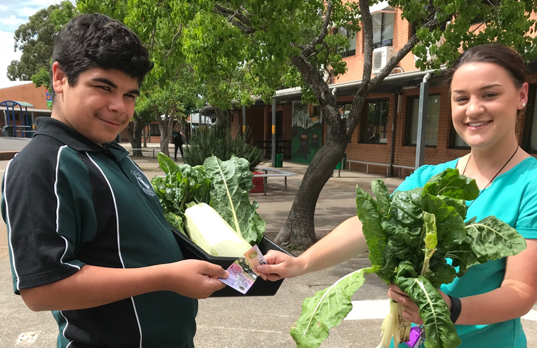 Nathaniel West-Doyle selling a freshly picked bunch of silverbeet to teacher Ms Agius